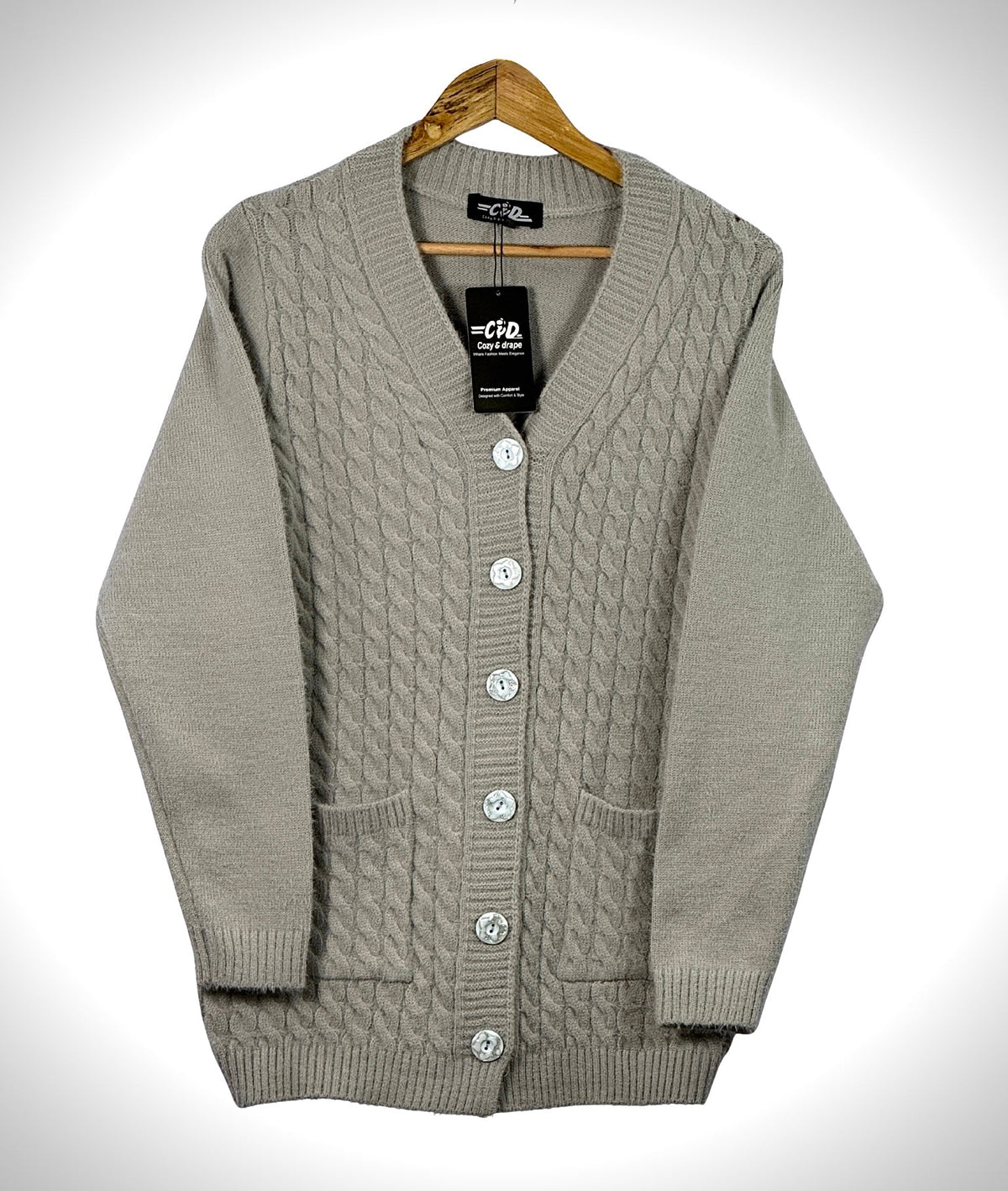Cozy&Drape beige cable knit cardigan sweater with front buttons and pockets on a wooden hanger