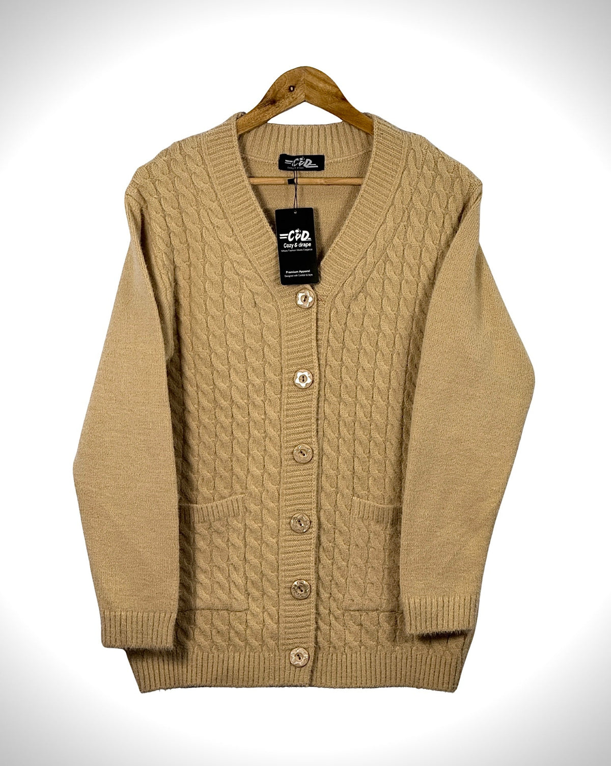 Cozy&Drape beige cable knit cardigan sweater with long sleeves, front buttons, and two pockets on a wooden hanger.