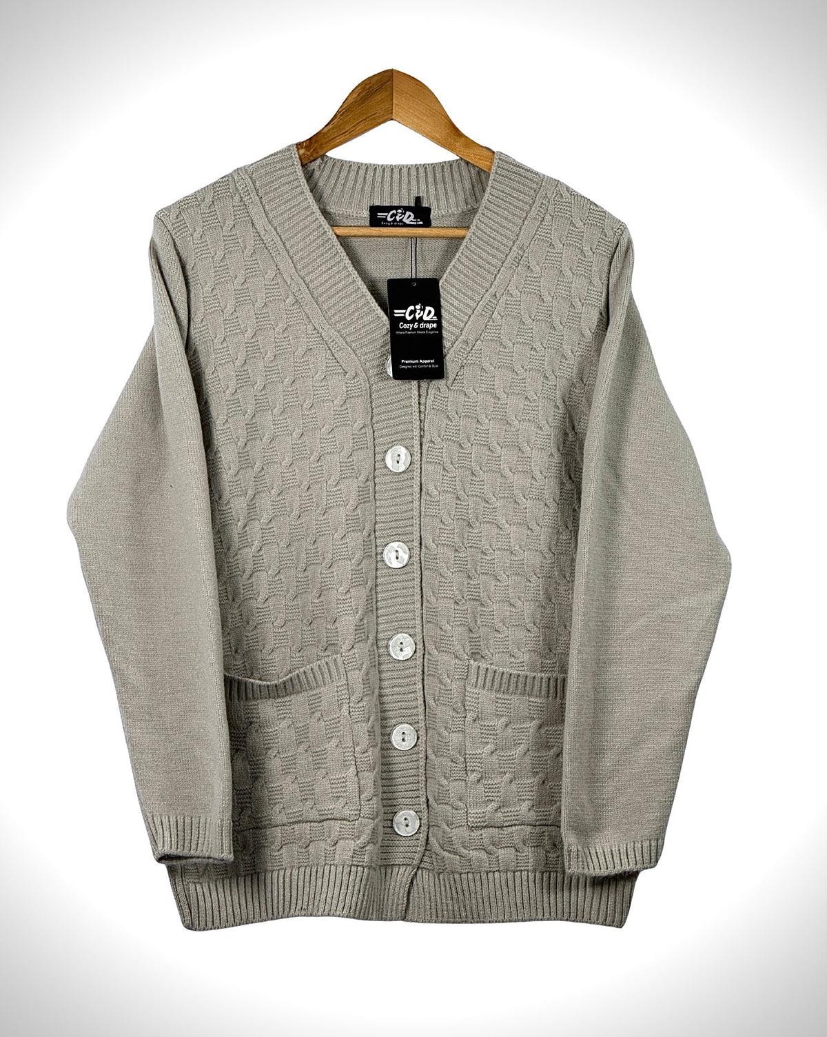 Cozy&Drape beige cable knit cardigan sweater with long sleeves, front buttons, and two pockets on a wooden hanger.