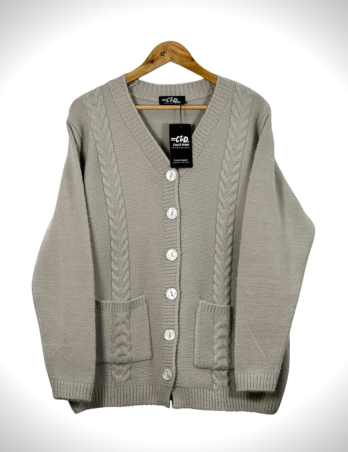 Cozy&Drape beige cable knit cardigan sweater with front buttons and pockets on a wooden hanger