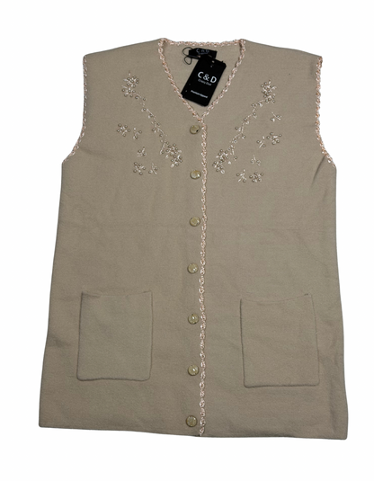 Cozy&Drape sleeveless wool cardigan in beige with floral embroidery, front buttons, and two patch pockets.