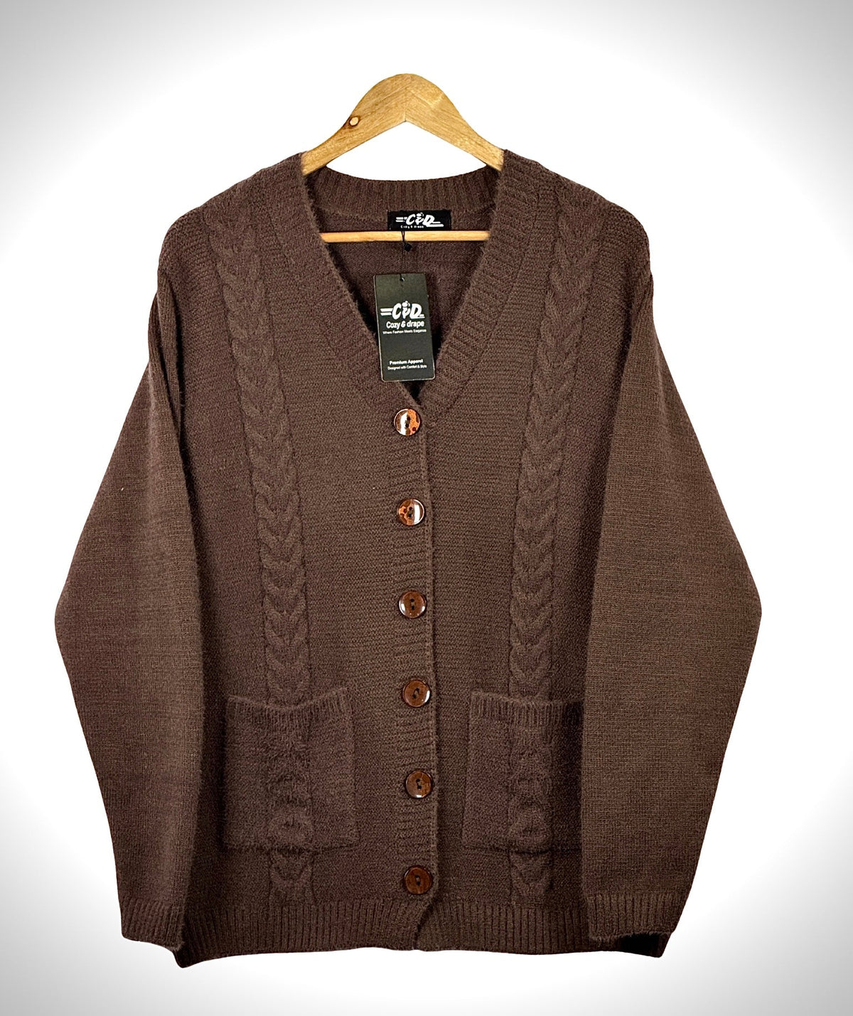 Cozy&Drape brown cable knit cardigan sweater with long sleeves, front buttons, and two pockets on a wooden hanger.