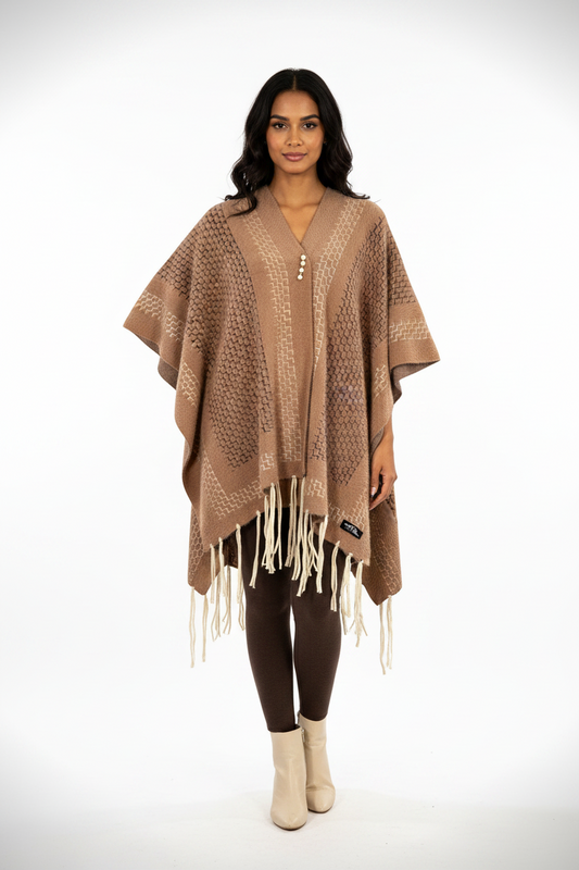 Model wearing a Cozy&Drape brown geometric patterned fringe poncho wrap with a pearl-style clasp over brown leggings.