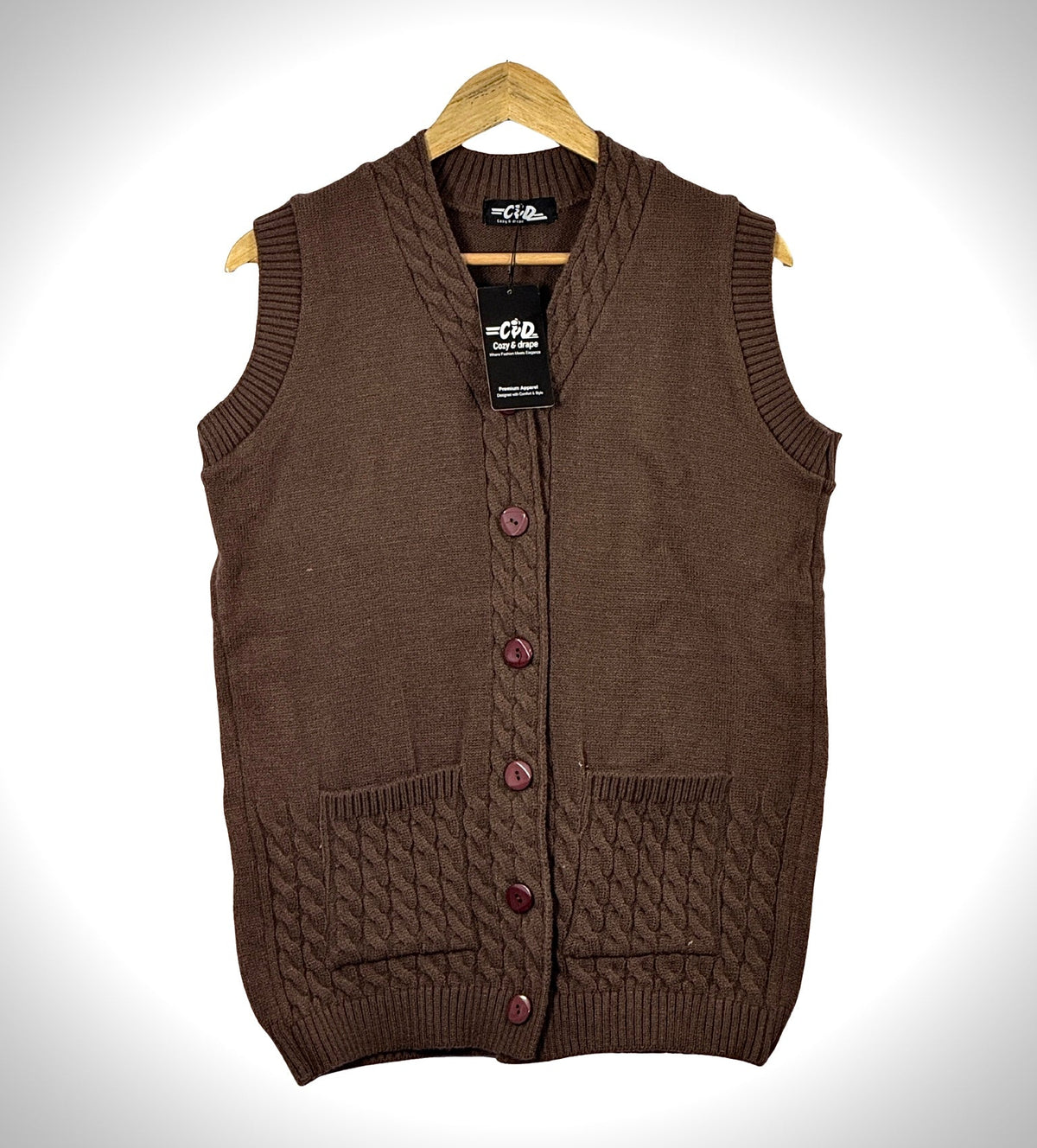 Cozy&Drape brown sleeveless cardigan sweater with front buttons, cable knit pockets, and ribbed trim on a hanger.