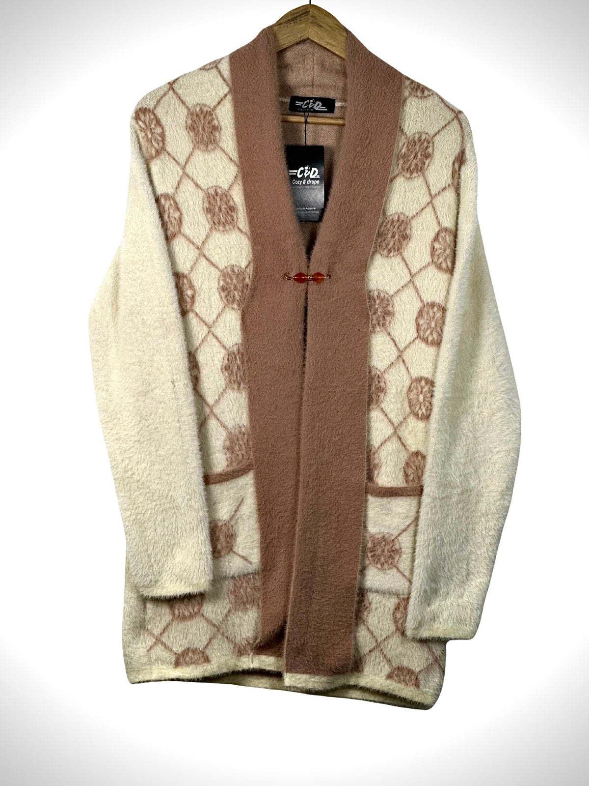 Cozy&Drape open front sweater in cream and brown with a geometric circle pattern and front pockets on a hanger