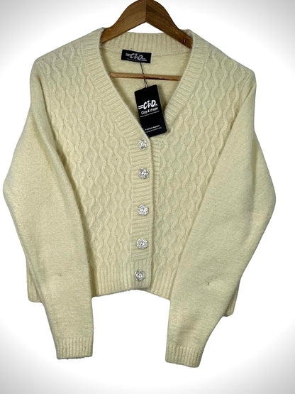 Cozy&Drape cream cable knit extra short cardigan sweater with decorative floral buttons on a wooden hanger