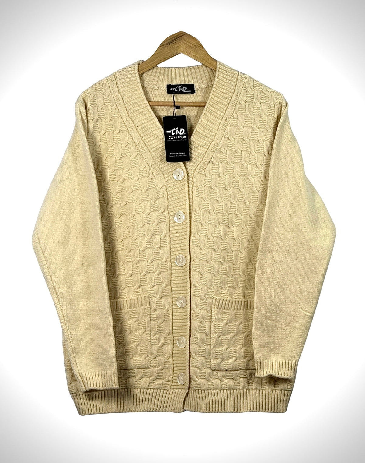 Cozy&Drape cream cable knit cardigan sweater with a V-neck, button-up front, and two patch pockets on a hanger.