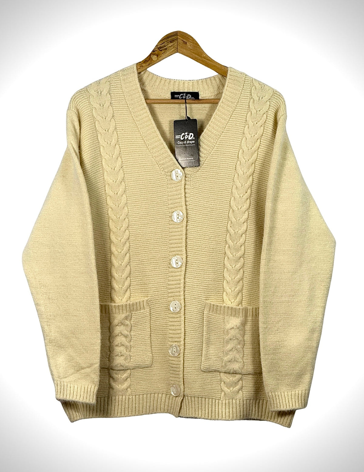 Cozy&Drape cream cable knit cardigan sweater with front buttons and pockets on a wooden hanger