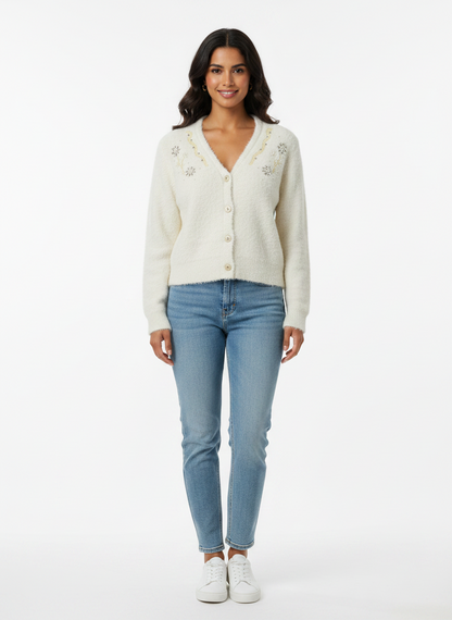 Model wearing a Cozy&Drape cream fuzzy knit cardigan with floral beadwork, V-neck, and buttons, paired with blue jeans.