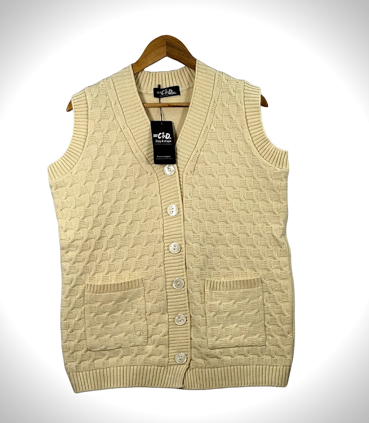 Cozy&Drape sleeveless cardigan sweater in cream with a cable knit pattern, button front, and two front pockets.