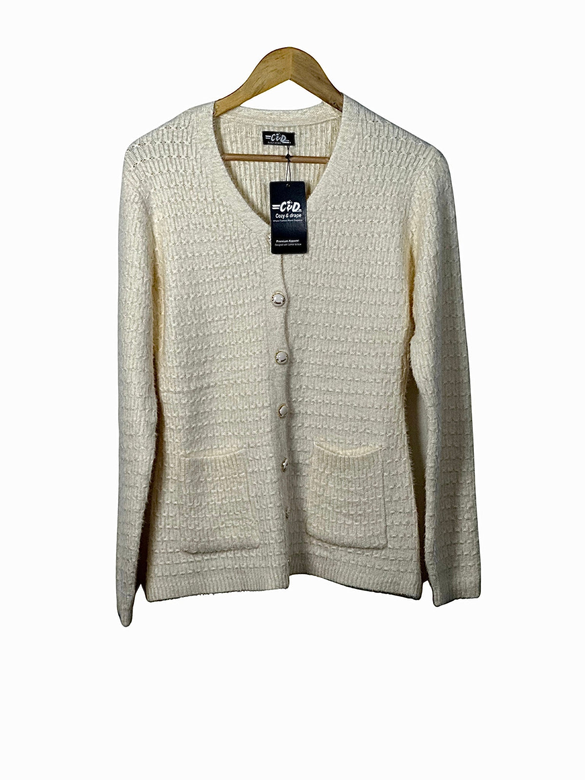 Cozy&Drape cream button-up cardigan sweater with textured knit fabric, V-neck, and two front pockets on a hanger.