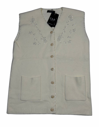 Cozy&Drape sleeveless wool cardigan in cream with floral bead embroidery, front buttons, and two patch pockets.