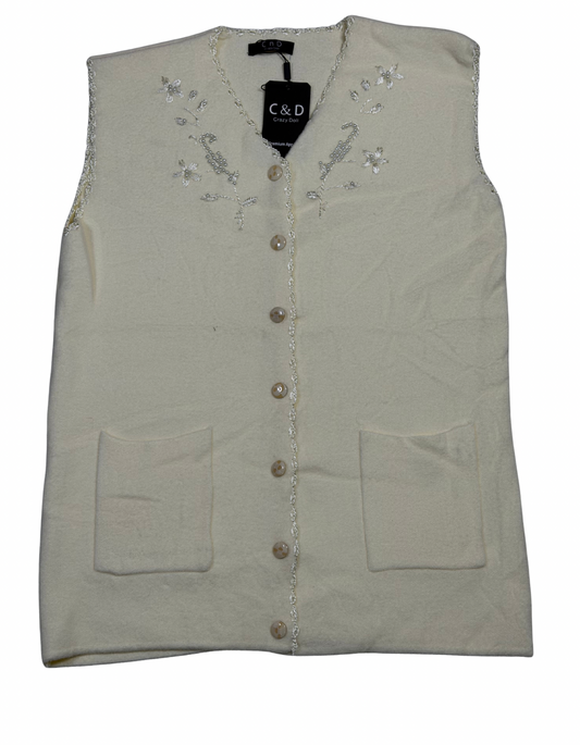Cozy&Drape sleeveless wool cardigan in cream with floral embroidery, front buttons, and two patch pockets.