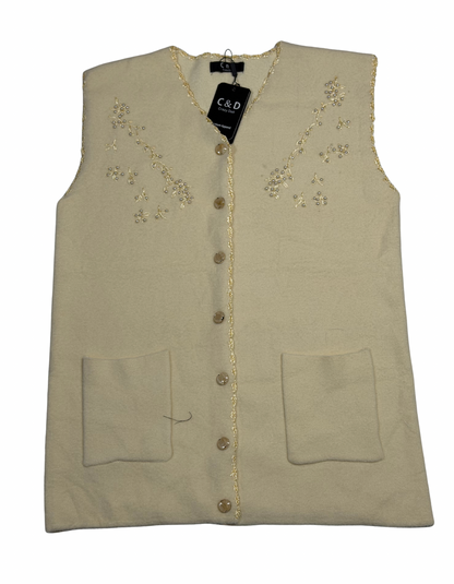 Cozy&Drape sleeveless wool cardigan in cream with floral embroidery, front buttons, and two patch pockets.