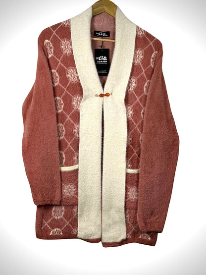 Cozy&Drape open front sweater in dusty rose with white floral pattern, cream trim, and front pockets on a hanger.