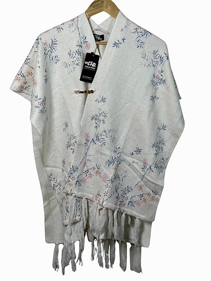 Cozy&Drape white winter cape shawl with delicate blue and pink floral pattern and fringe hem detail