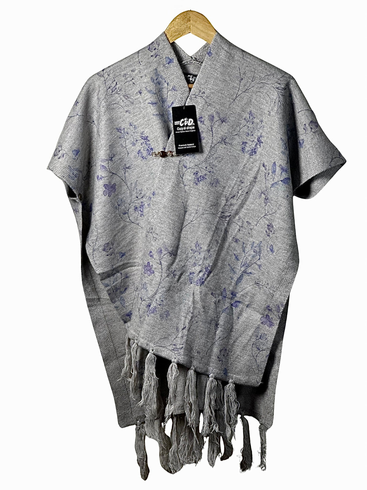 Cozy&Drape grey cape shawl with blue floral print, featuring a decorative clasp and fringe hem on a wooden hanger.