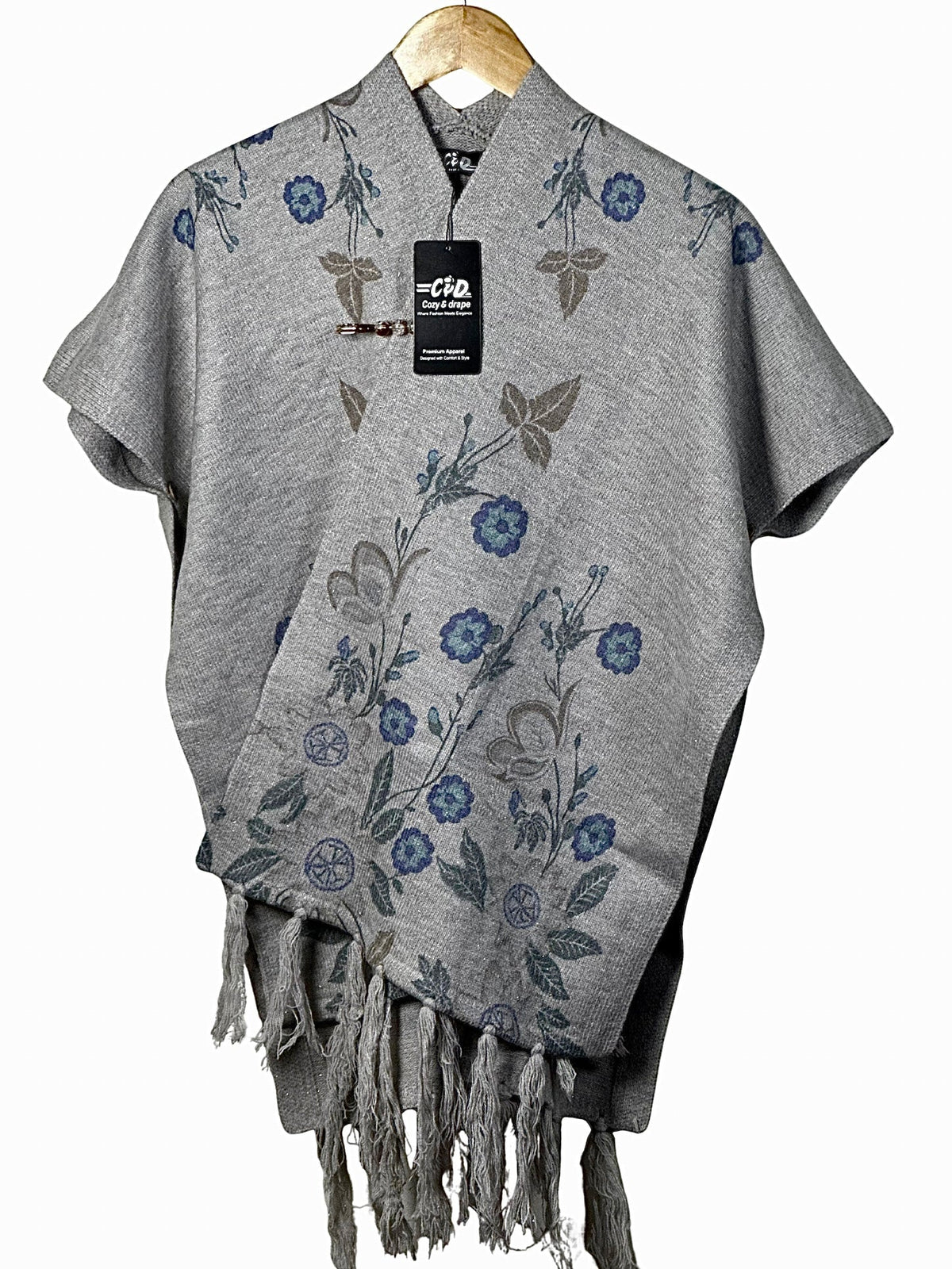 Cozy&Drape grey floral cape shawl with fringe hem and elegant winter design on a wooden hanger