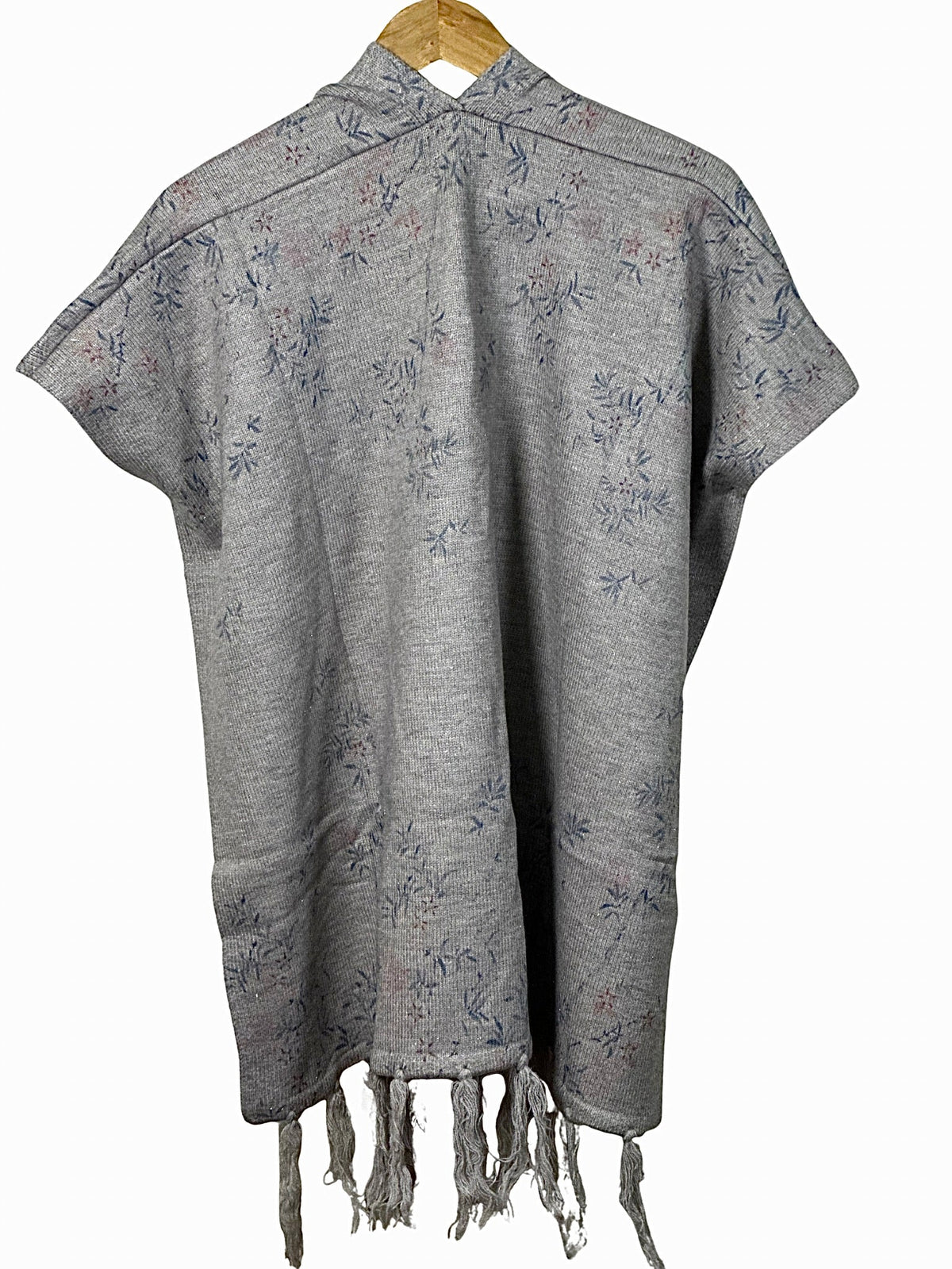 Cozy&Drape grey winter cape shawl with delicate floral pattern and fringe hem, hanging on a wooden hanger