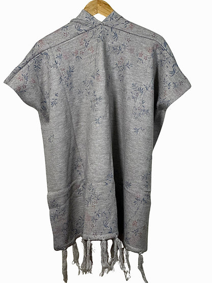 Cozy&Drape grey winter cape shawl with delicate floral pattern and fringe hem, hanging on a wooden hanger