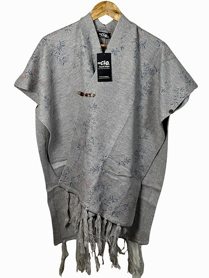Cozy&Drape grey winter cape shawl with delicate floral print, button detail, and fringe hem on a wooden hanger.