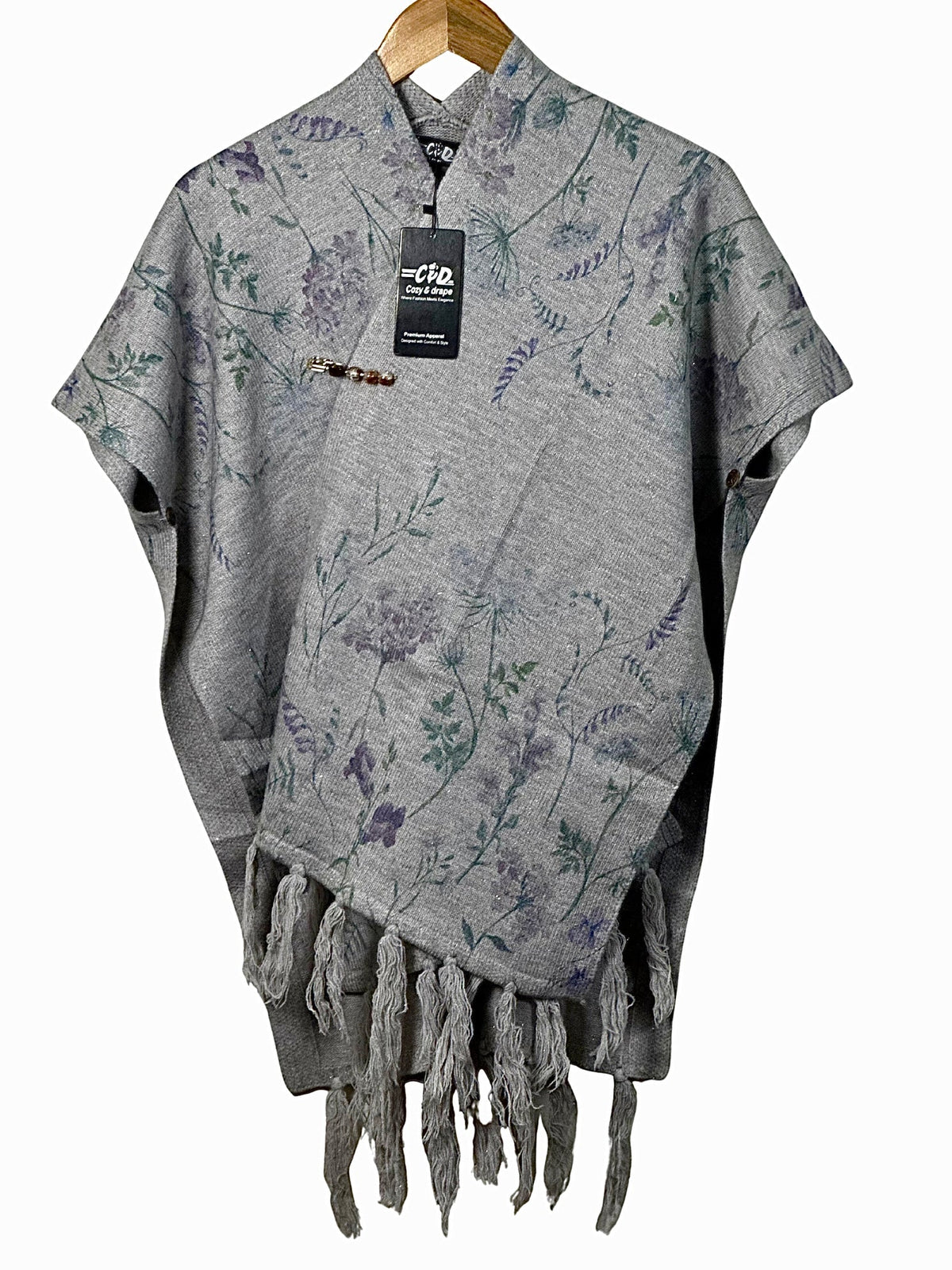 Cozy&Drape grey cape shawl featuring a delicate purple and green floral print with fringe trim and a decorative pin.