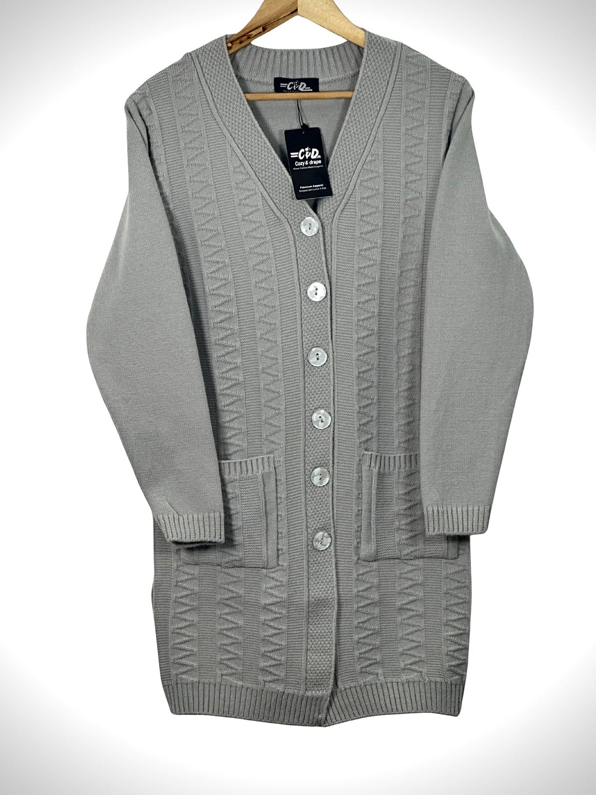 Cozy&Drape grey long-line knit cardigan with V-neck, button-front closure, and two front pockets on a wooden hanger.