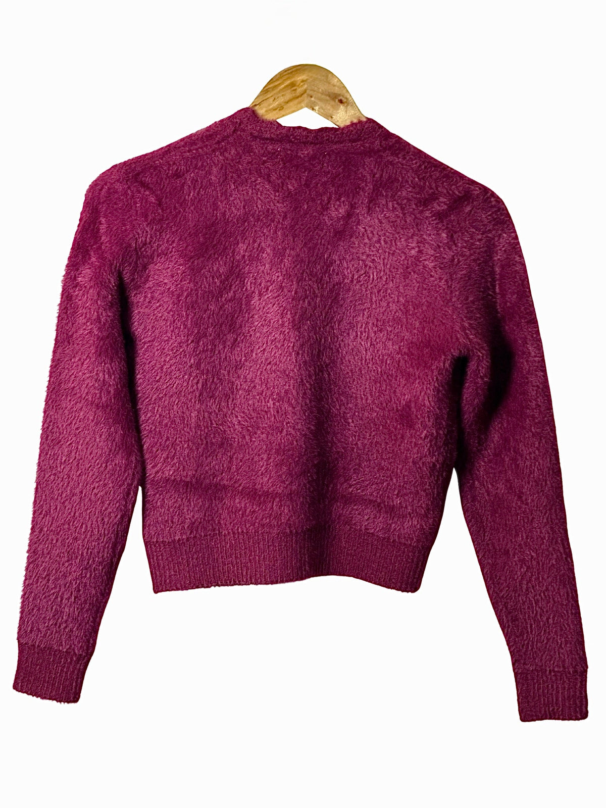 Cozy&Drape extra short fuzzy cardigan sweater in deep magenta with long sleeves and ribbed hem on a wooden hanger