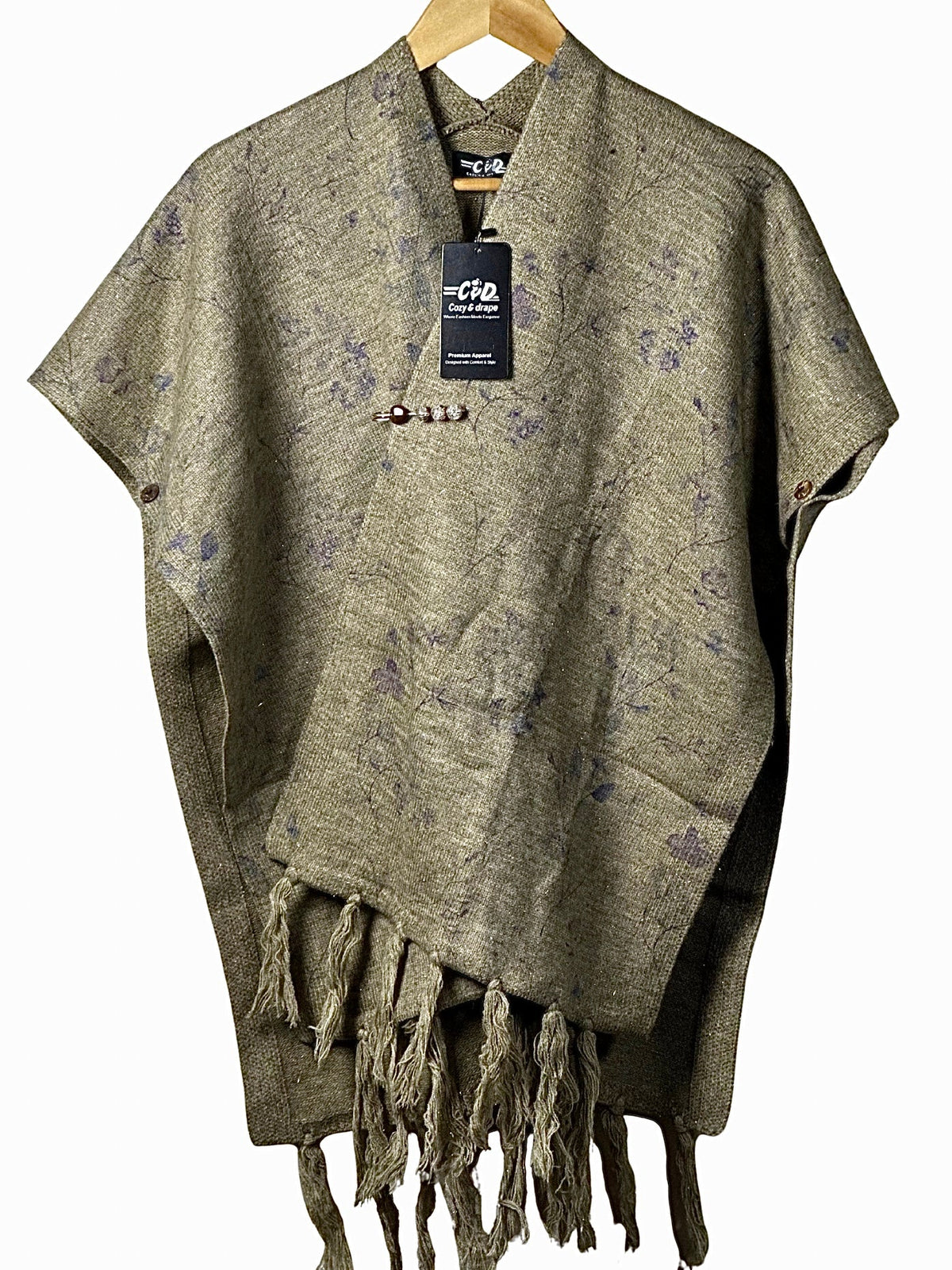 Cozy&Drape olive green winter cape shawl with floral pattern, tassel hem, and decorative brooch on a wooden hanger
