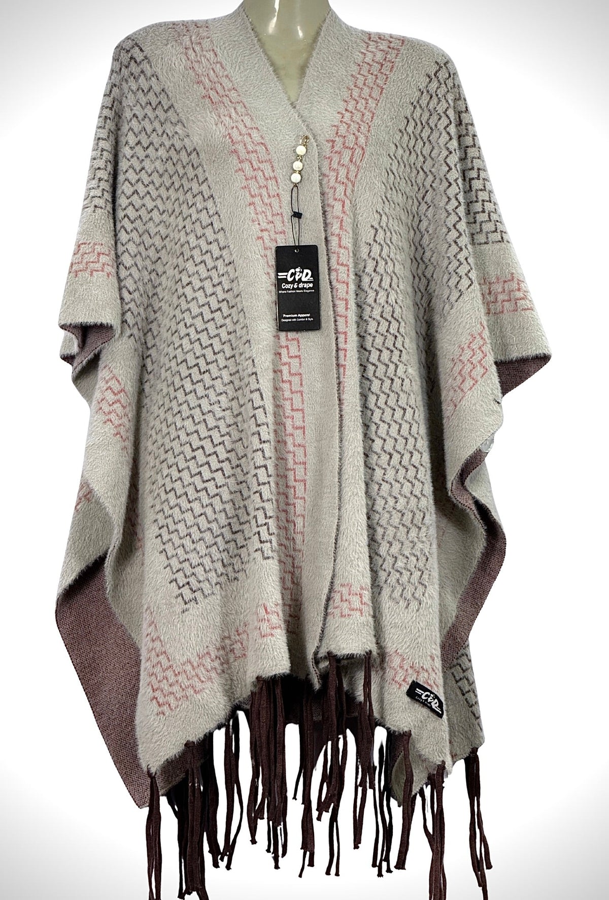 Cozy&Drape beige winter cape shawl with geometric patterns, soft knit texture, and dark brown fringe trim.