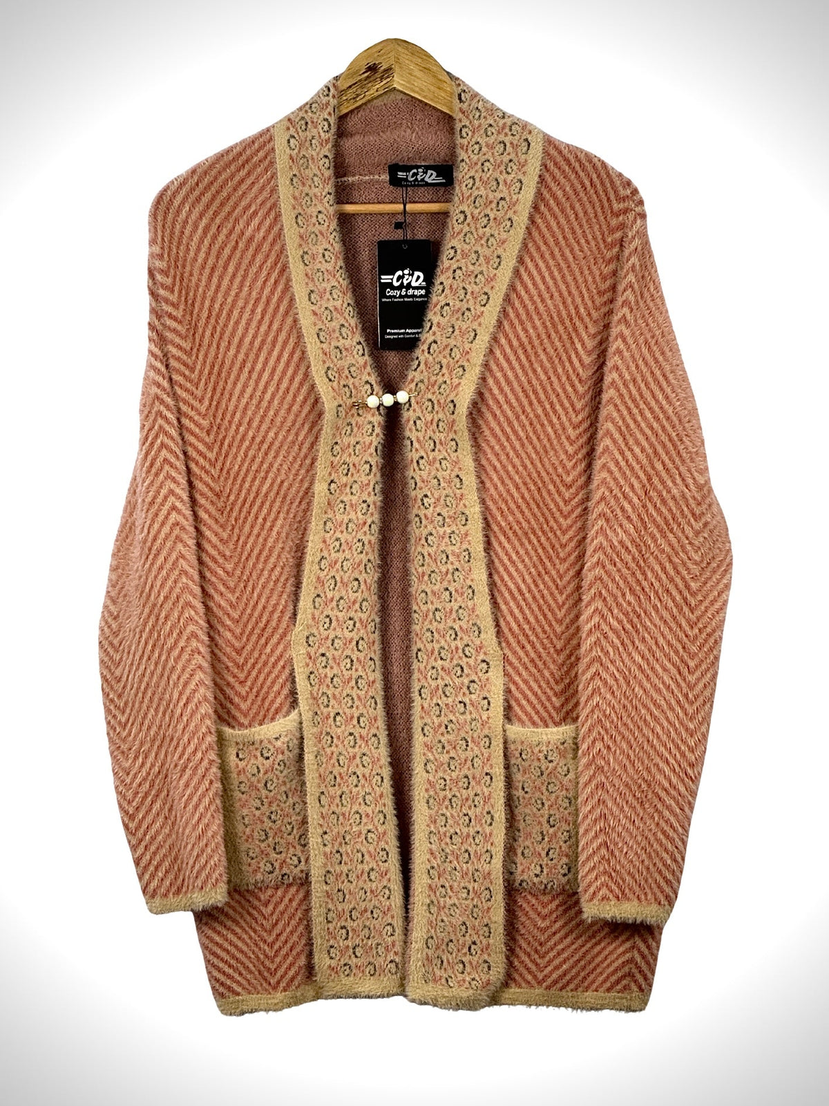 Cozy&Drape open front sweater in peach with a chevron pattern, beige trim, and two front pockets on a wooden hanger.