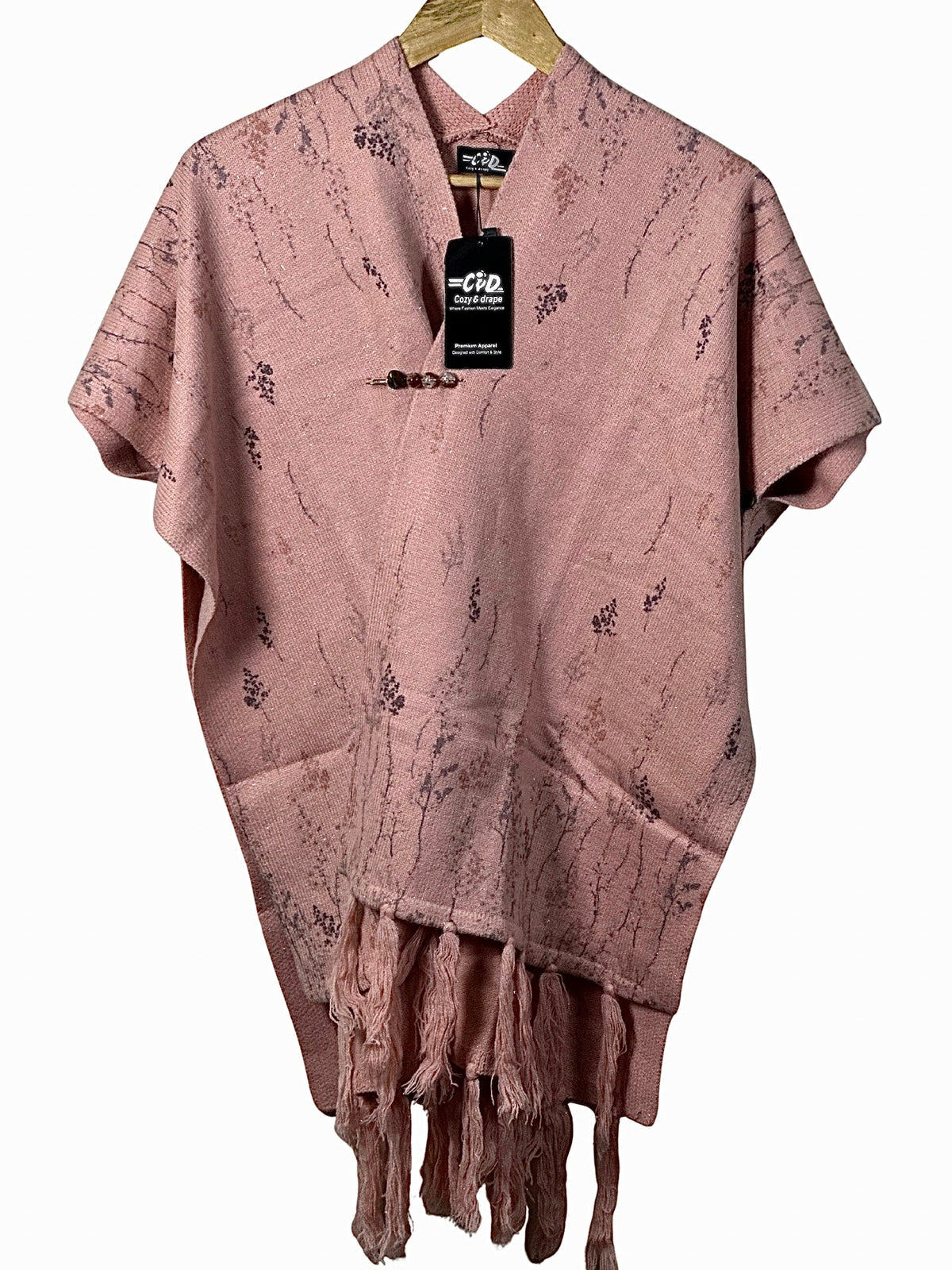 Cozy&Drape dusty pink knit cape shawl with delicate floral patterns, fringe hem, and a decorative toggle closure.