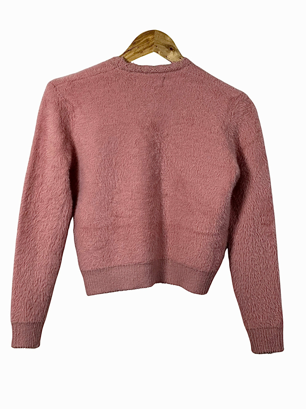 Cozy&Drape extra short pink fuzzy cardigan sweater with long sleeves and ribbed hem on a wooden hanger