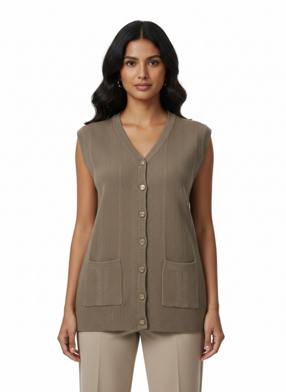 Model wearing a Cozy&Drape sleeveless taupe knit cardigan with a V-neck, button front, and two front patch pockets.