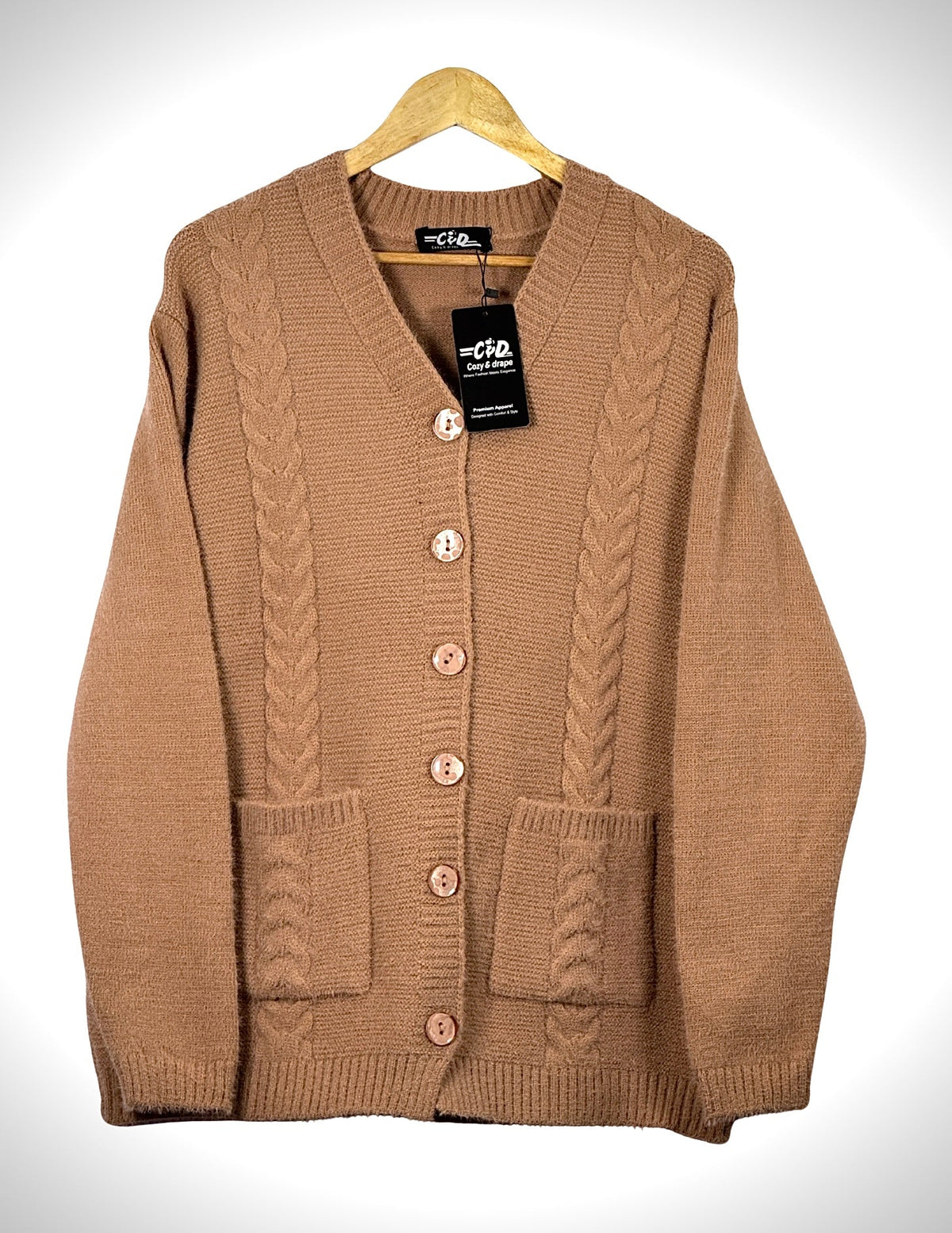 Cozy&Drape tan cable knit cardigan sweater with full sleeves, front buttons, and two patch pockets on a hanger.