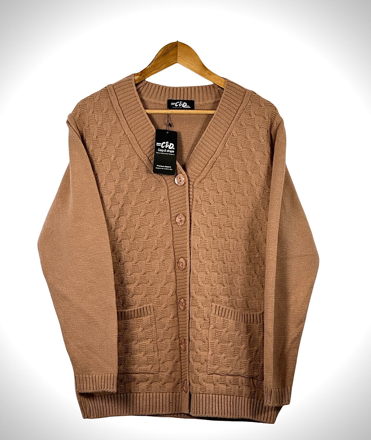 Cozy&Drape tan cable knit cardigan sweater with long sleeves, button front closure, and two front pockets on a hanger