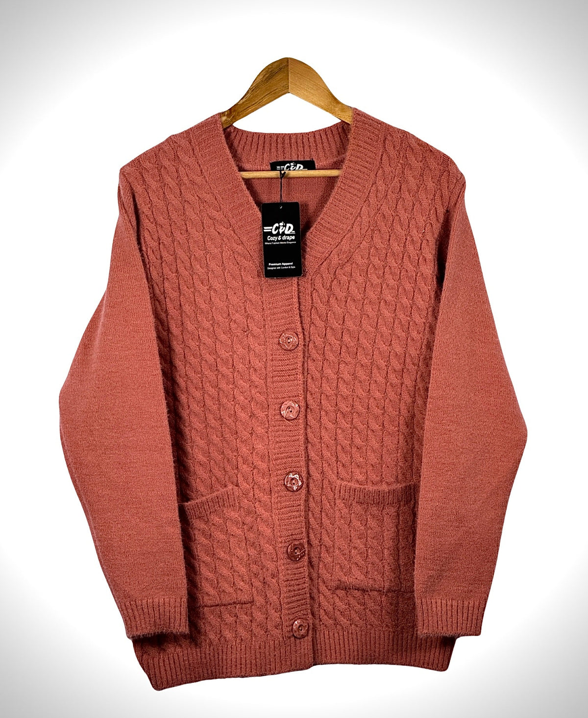 Cozy&Drape terracotta cable knit cardigan sweater with long sleeves, front buttons, and two pockets on a hanger.